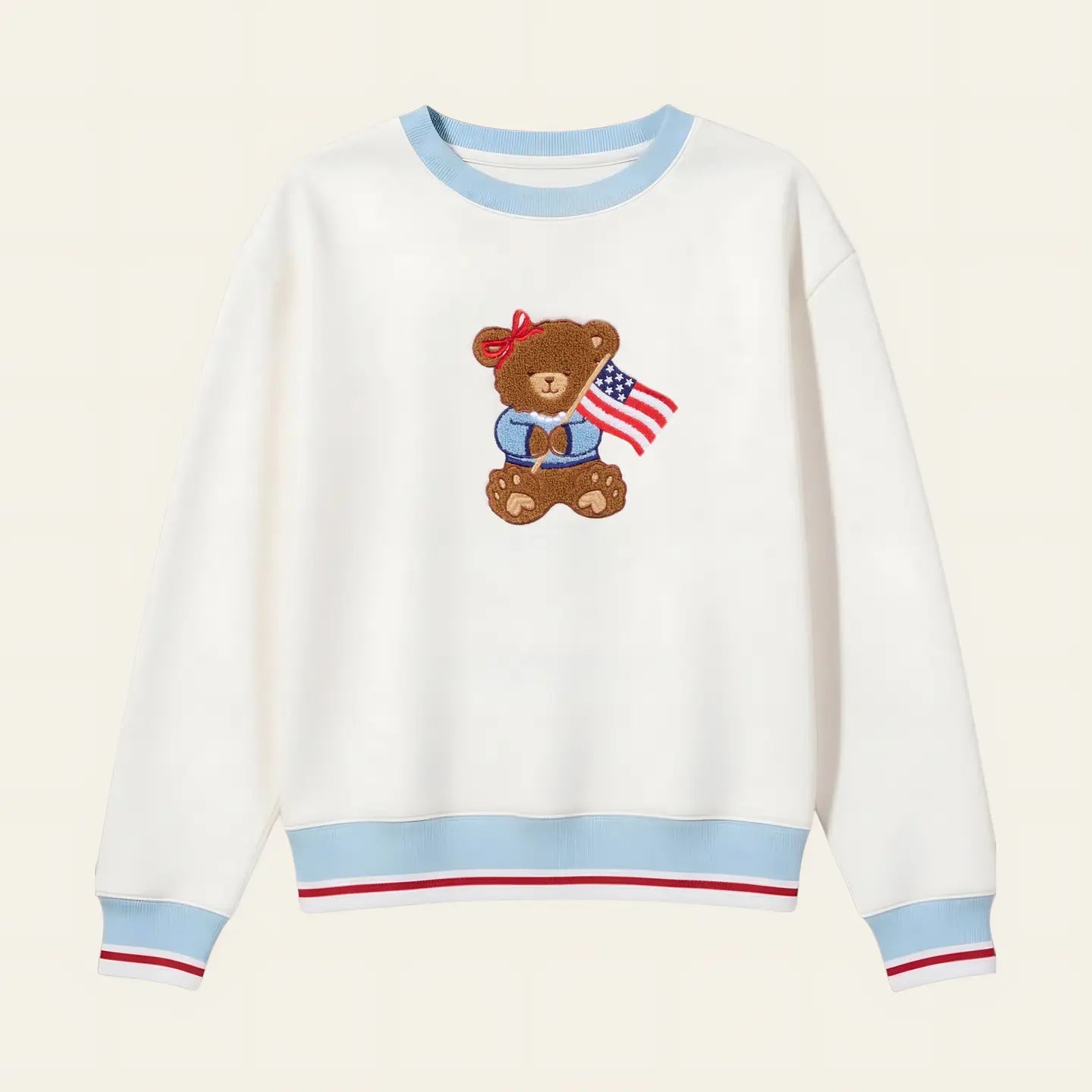 White sweatshirt with a teddy bear design holding an American flag on a beige background