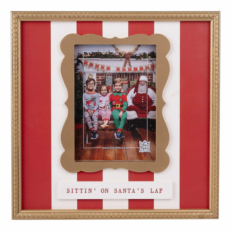 A festive gold picture frame with red and white striped matting and the text 'SITTIN' ON SANTA'S LAP' at the bottom, holding a holiday family photo.