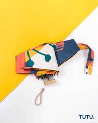 Colorful umbrella with abstract design on a yellow and white background, featuring the brand 'TUTU'.