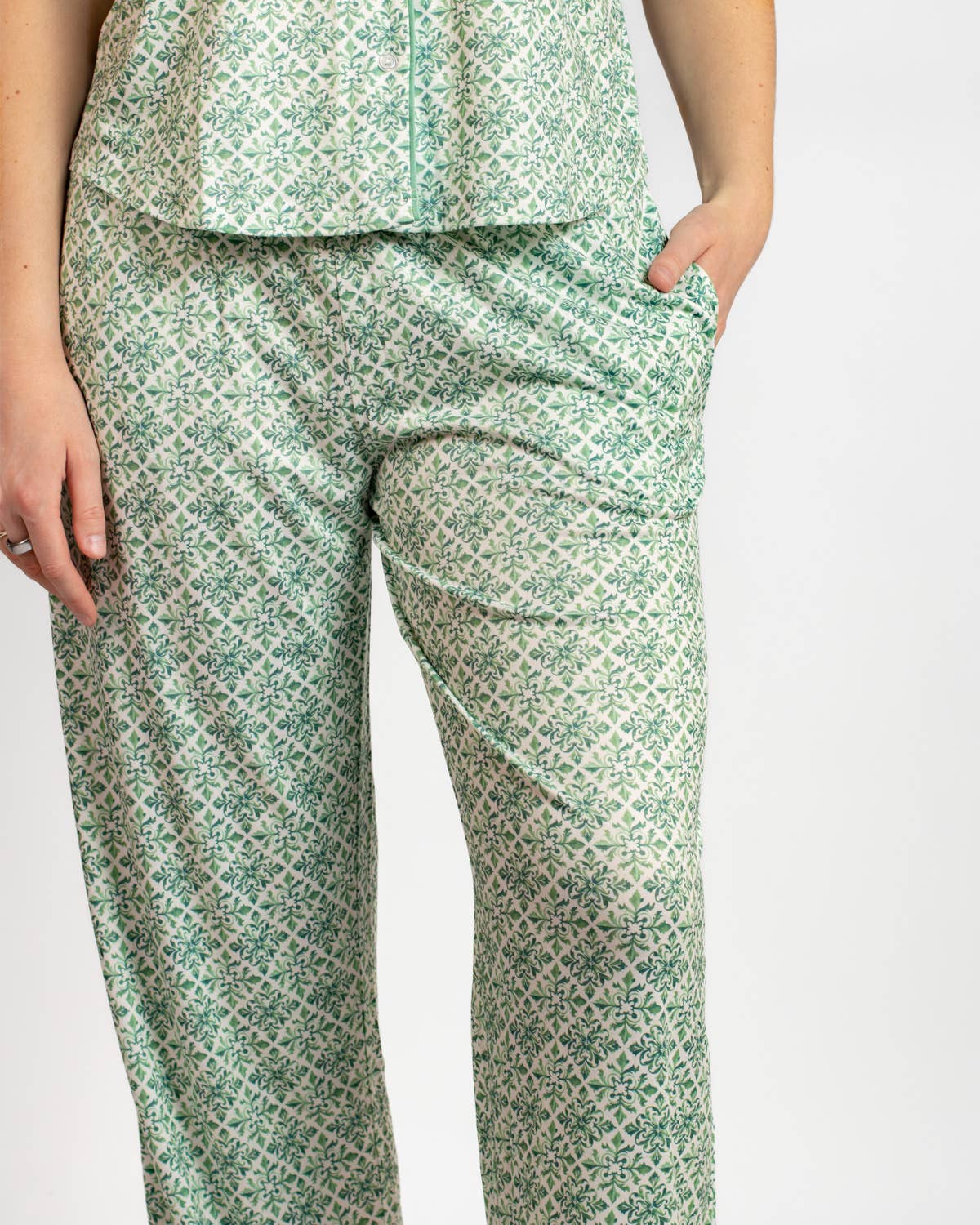 Green patterned pants worn by a person on a white background