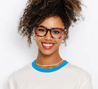 Woman wearing colorful glasses and a white shirt with blue collar against a light background