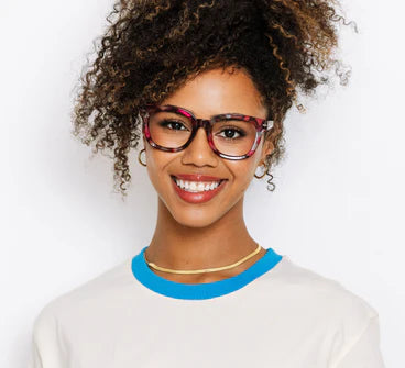 Woman wearing colorful glasses and a white shirt with blue collar against a light background