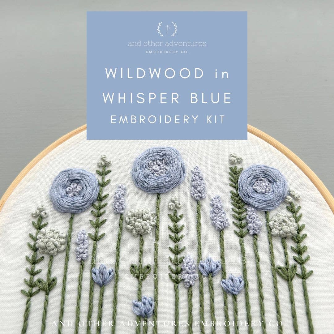 Embroidery kit with floral design and 'Wildwood in Whisper Blue' text on a gray background