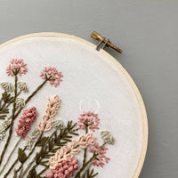 Embroidery hoop with floral embroidery on a gray background