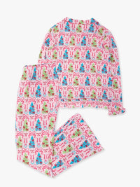 A two-piece pajama set featuring a long-sleeve top and matching pants in a pink and white pattern with blue and green Christmas trees, bows, and candy canes, laid flat on a light gray background.