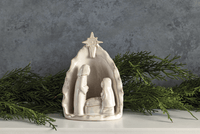 Nativity scene figurine with a gray background and greenery