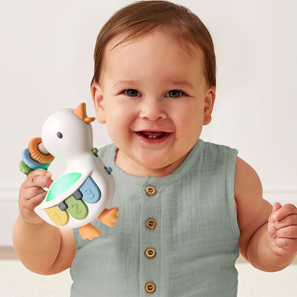 Baby holding a colorful toy with a plain background