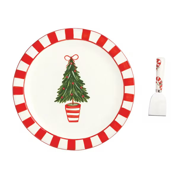 A holiday-themed dinnerware set featuring a white plate with a red and white striped border and a green Christmas tree illustration, accompanied by a white spatula with a red and white striped handle.