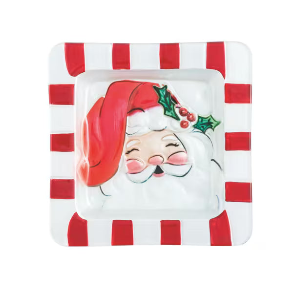 A square white ceramic dish with red and white striped borders, featuring a raised relief of Santa Claus's face wearing a red hat with green holly leaves and red berries.