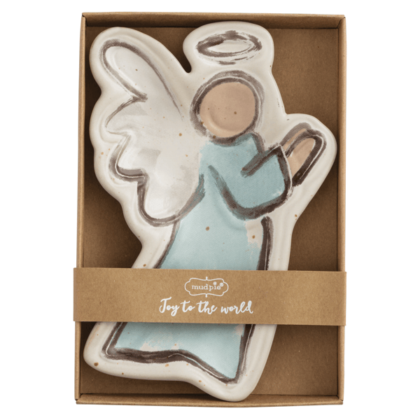 A ceramic angel-shaped candle in a brown gift box with a kraft paper band reading 'made in UK Joy to the world'. The candle has a white body with a light blue dress and brown outline details.