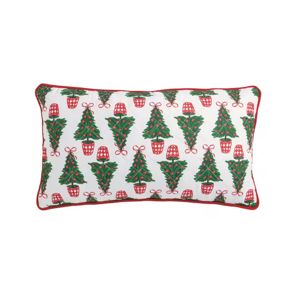 A rectangular decorative throw pillow with a white background, featuring a repeating pattern of green Christmas trees, red plaid stockings, and red bows, finished with a red piped border.