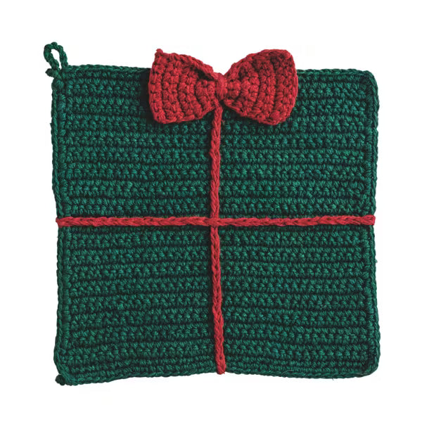 A crocheted square pot holder designed to look like a wrapped gift, featuring a dark green body with a red bow and red cross-section representing the wrapping ribbon, shown on a plain white background.