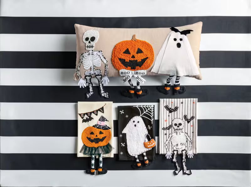 Halloween-themed decorative pillows and plush toys on a black and white striped background