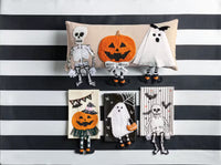 Halloween-themed decorative pillows and plush toys on a black and white striped background