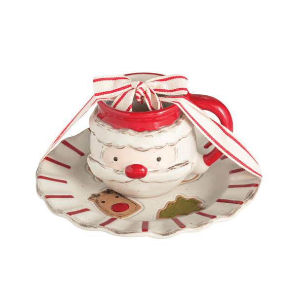 A festive ceramic Santa mug on a matching saucer, decorated with a red and white striped ribbon bow. The mug features a white body with red accents, a red nose, and a painted Santa face, while the saucer includes holiday illustrations like a reindeer and a Christmas tree.