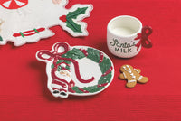 Christmas-themed plate, cup, and cookies on a red background