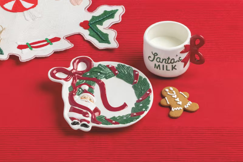 Christmas-themed plate, cup, and cookies on a red background