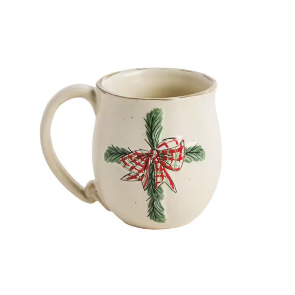 An off-white ceramic mug featuring a hand-painted green pine branch with a red and white plaid bow on the front, set against a plain white background.