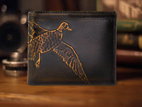 Black leather wallet with a gold duck design on a wooden surface