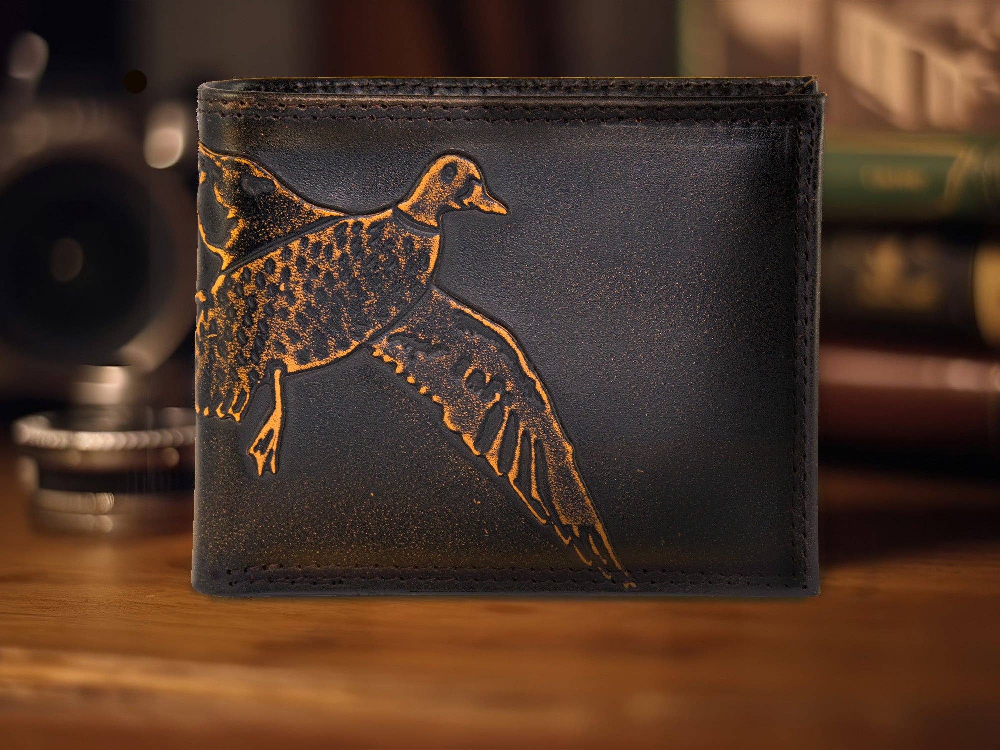 Black leather wallet with a gold duck design on a wooden surface