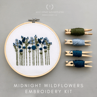 Embroidery hoop with embroidered wildflowers and embroidery thread on a gray background