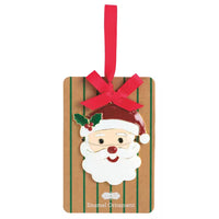 A rectangular enamel Christmas ornament shaped like a gift box with green vertical stripes, featuring a Santa Claus face with a red hat, white beard, and holly leaf, hanging from a red ribbon bow.