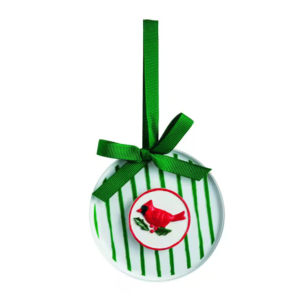 A round white Christmas ornament with green vertical stripes, a green ribbon bow, and a red cardinal bird illustration in the center, shown on a plain white background.