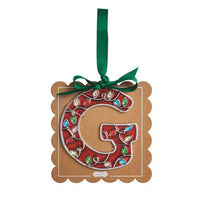 A decorative hanging ornament shaped like the letter G, made from brown kraft cardstock with a red glitter center, silver trim, and colorful jewel embellishments. A green ribbon is tied at the top for hanging.