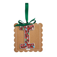 A decorative hanging ornament shaped like the letter I, made from red glittery material with colorful rhinestone-like accents, attached to a brown scalloped gift tag with a green ribbon loop.