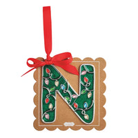 A decorative hanging ornament shaped like the letter N, with a green glittery center decorated with colorful Christmas lights and a red ribbon loop at the top, mounted on a scalloped brown kraft card background.