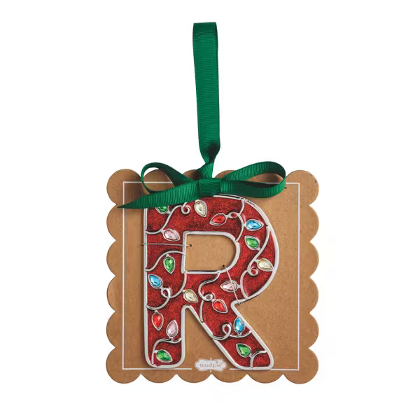 A decorative hanging ornament shaped like the letter R on a kraft paper tag with scalloped edges, decorated with a red Christmas lights pattern and a green ribbon loop at the top.