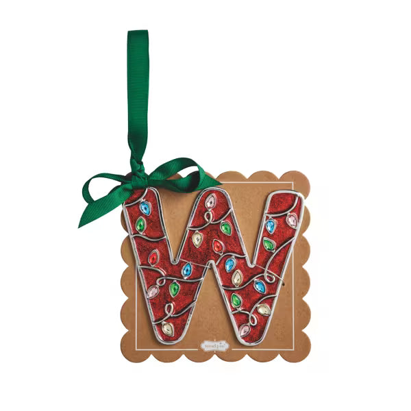 A decorative hanging ornament shaped like the letter W, made from red textured material with colorful jewel-like accents, mounted on a brown scalloped backing card with a green ribbon loop.