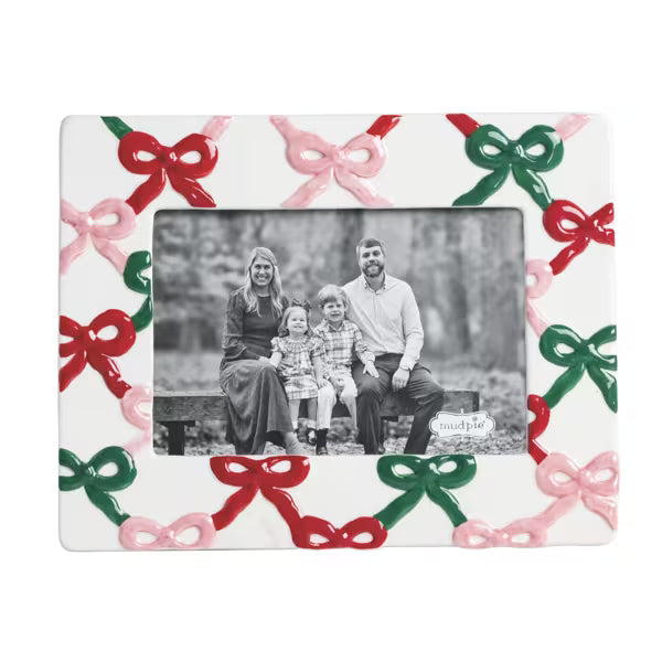 A square white ceramic picture frame decorated with raised red, green, and pink bow patterns around the border. The center is open to display a black-and-white family photograph.