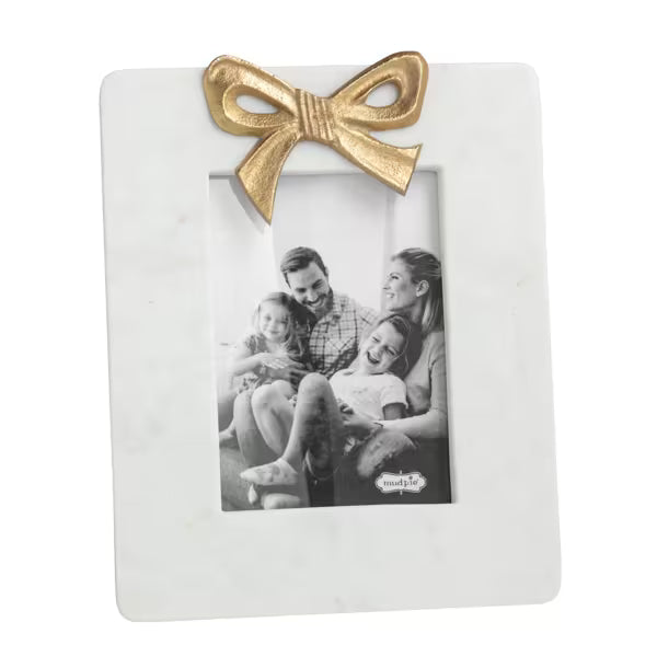 A white marble-look rectangular photo frame with a metallic gold bow at the top, holding a black-and-white family photograph. The frame is photographed on a clean white background.