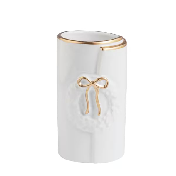 A white cylindrical ceramic container with a gold metallic rim and a gold bow detail on the front, set against a plain white background.