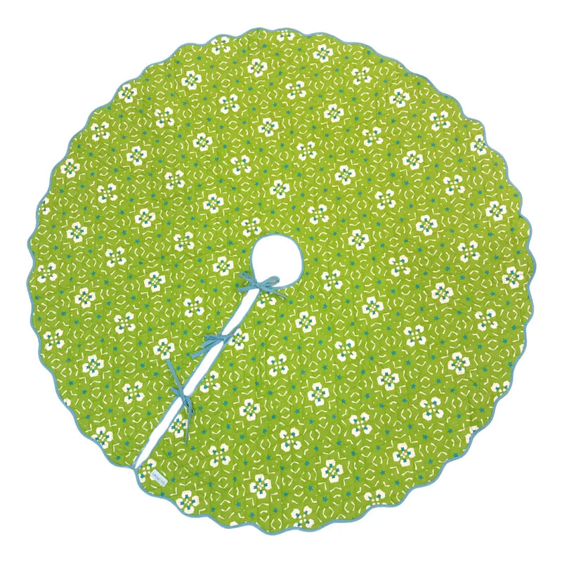 A round green tree skirt with a white and green floral pattern, featuring a scalloped edge and a central hole tied with a white ribbon.