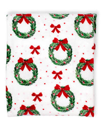 Christmas-themed fabric with wreaths and red bows on a white background