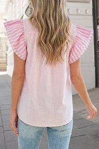 Person wearing a pink and white striped shirt with ruffled sleeves outdoors.