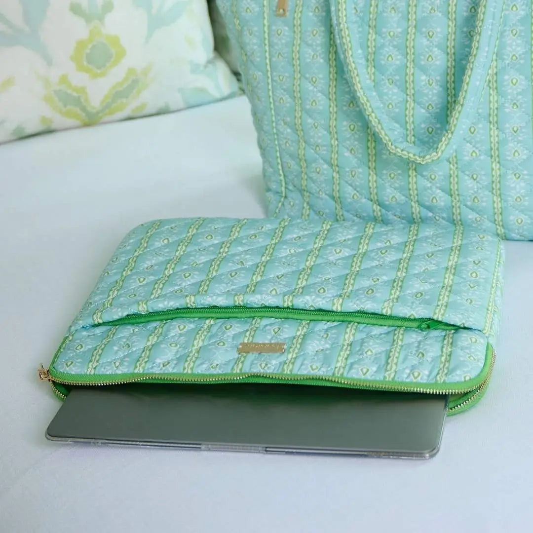 Light blue laptop sleeve with green zipper on a light surface