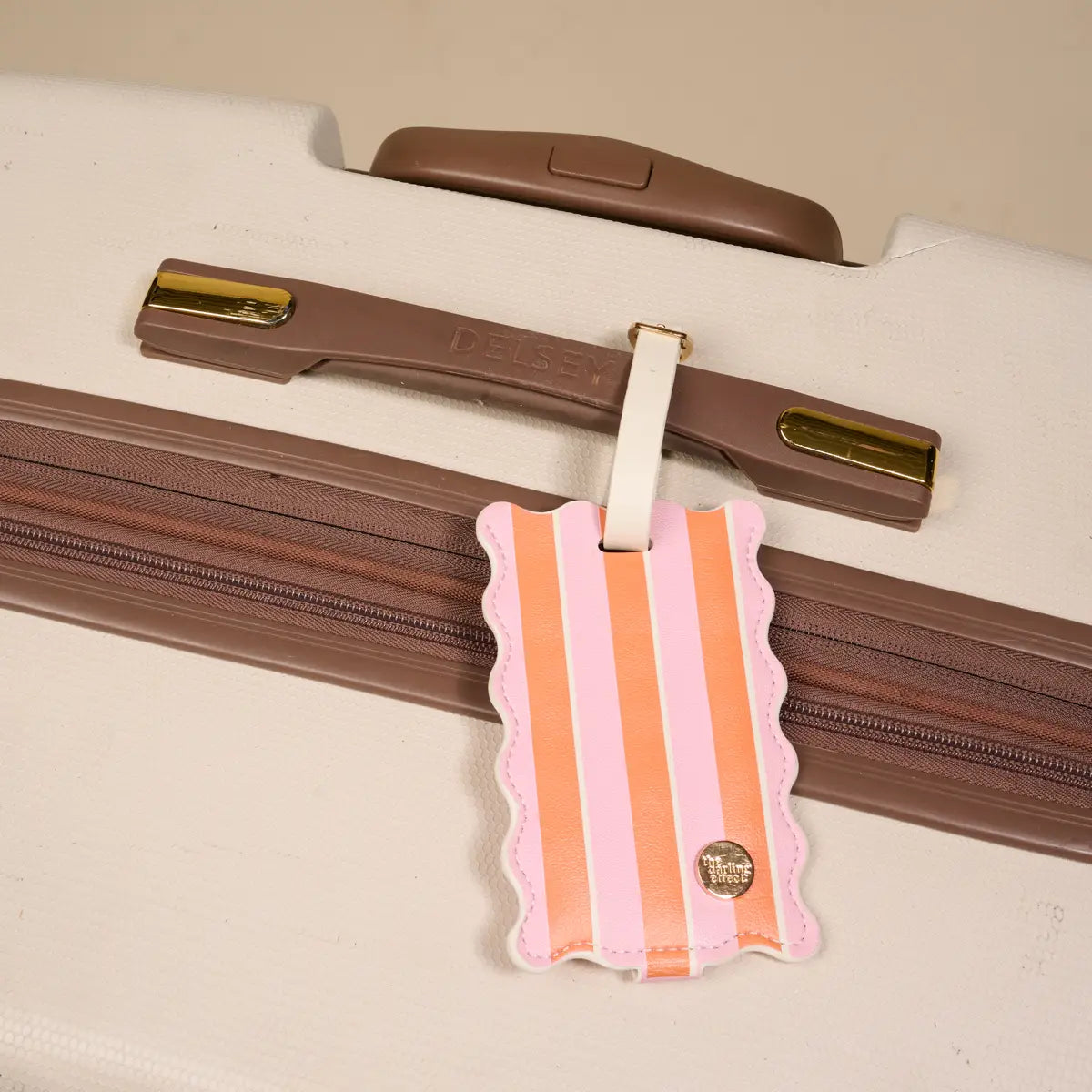 Striped luggage tag attached to a suitcase with a beige background