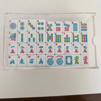Set of Mahjong tiles in a clear plastic case on a white background