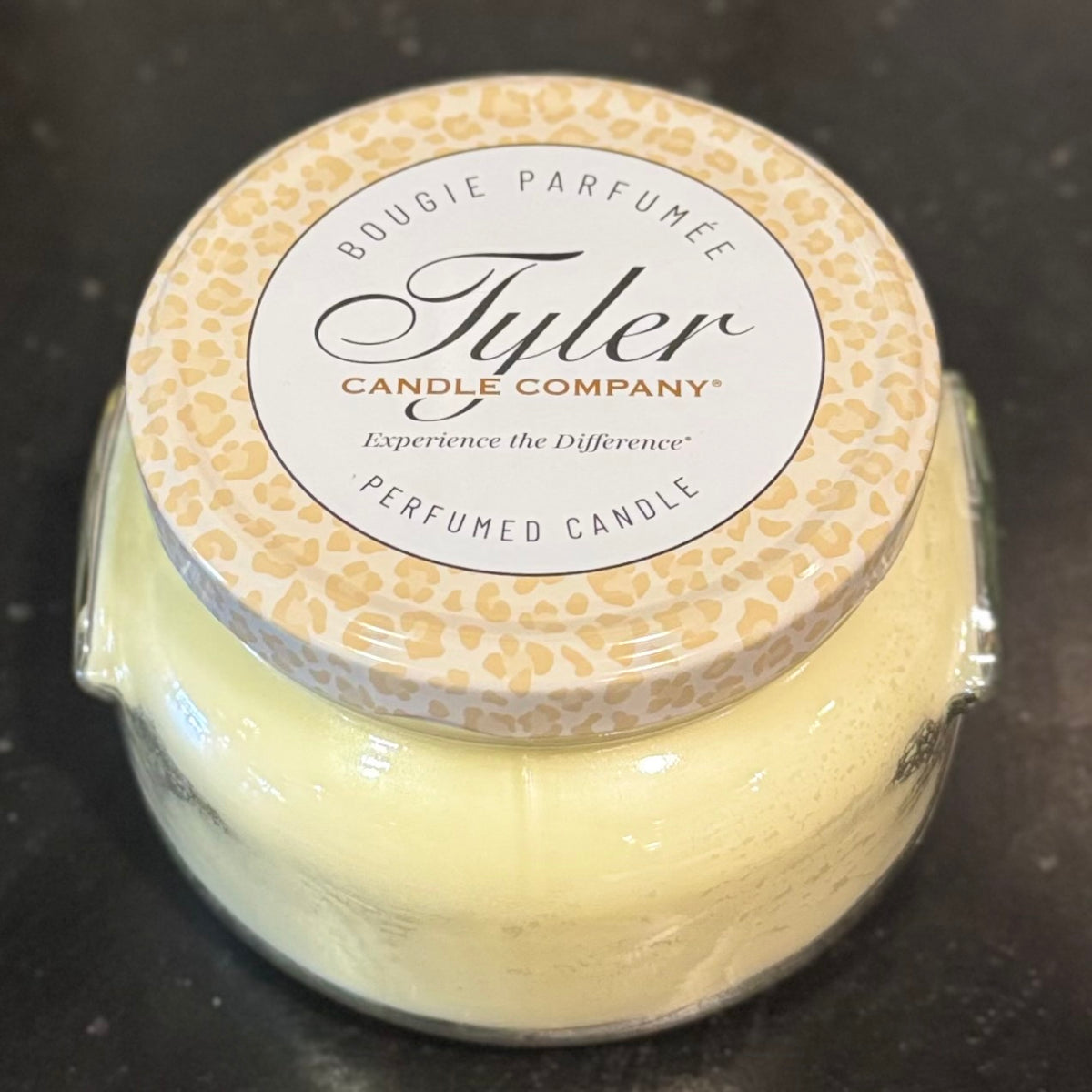 Tyler Candle Company candle with patterned lid on a dark surface