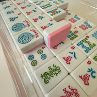 Close-up of a set of colorful Mahjong tiles with a pink tile on top.