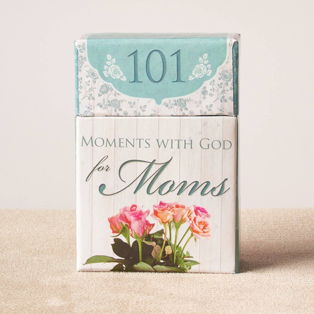 Book titled '101 Moments with God for Moms' with floral design on a beige background
