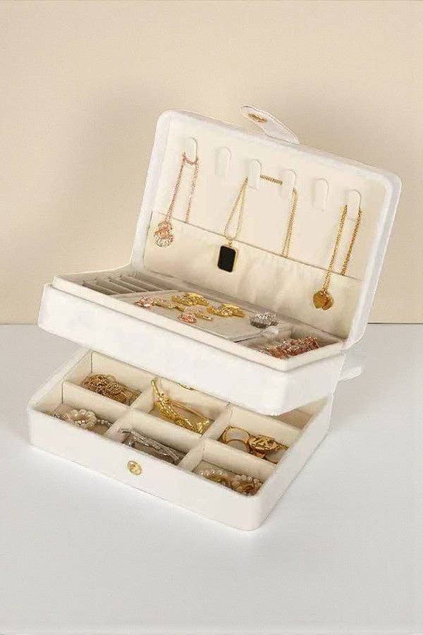 White jewelry box with jewelry on a light beige background