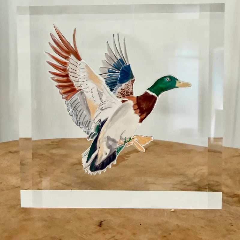 A colorful acrylic block featuring a flying mallard duck, displayed on a wooden surface against a white background.