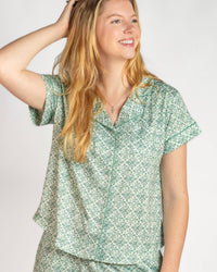 Woman wearing a green patterned shirt against a white background