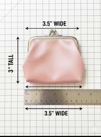 Pink coin purse with measurements on a grid background