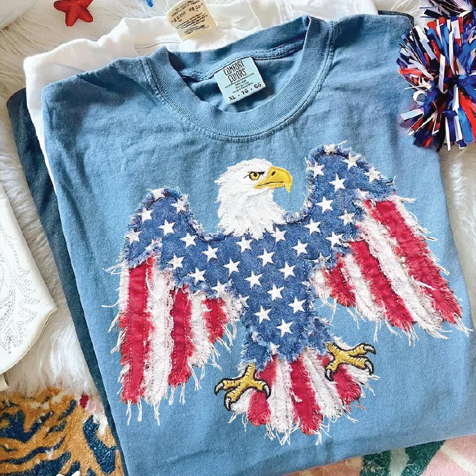 Blue t-shirt with an eagle design featuring the American flag on a textured surface.