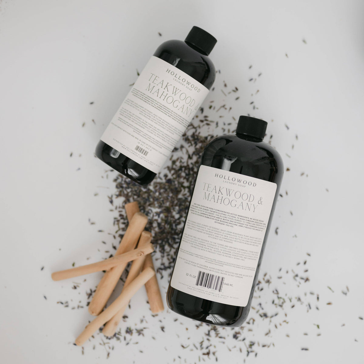 Two bottles of Hollywood Soap Company's Peakwood & Mahogany soap on a light background with wooden sticks and lavender.